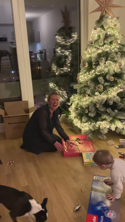 Încarcă clipul video: Das Video beginnt mit einer gemütlichen, festlichen Szene: Irena sitzt in einem warm beleuchteten Wohnzimmer, geschmückt mit Weihnachtsdekorationen. Ihr Mann Goran, begleitet von Achim und Jörg, überreicht ihr liebevoll verpacktes Geschenk.Irena öffnet das Geschenk und entdeckt ein einzigartiges 3D-Wimmelbild – ein Kunstwerk voller liebevoll eingefangener Erinnerungen. Ihre Augen leuchten vor Freude, und ein breites Lächeln breitet sich auf ihrem Gesicht aus.Das Bild zeigt in lebendigen Details ihre schönsten Momente, sorgfältig in einem Kunstwerk zusammengefügt. Die Kamera fängt die Emotionen ein – Freude, Staunen und Lachen erfüllen den Raum. Es ist ein Moment, der Herzen erwärmt und die Magie des Schenkens einfängt.Begleitet wird das Video von einem rhythmischen, emotionalen Text, der die Bedeutung von Erinnerungen und personalisierten Geschenken betont. Der Bildschirm blendet den Slogan ein: „Dein Moment, dein Kunstwerk“ und leitet mit einem sanften Übergang zur Website www.createyourwimmel.de, während sanfte Musik im Hintergrund spielt.Am Ende des Videos leuchtet die Botschaft auf: „Die schönsten Momente als 3D-Wimmelbild – ein Geschenk für die Ewigkeit.“
